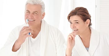Senior man and woman brushing teeth