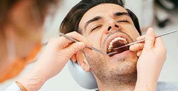 Man in dental chair examined by dentist