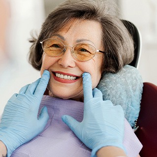 Dentist with blue gloves looking at senior woman's smile