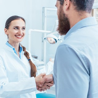 Dentist and patient engaging in friendly handshake