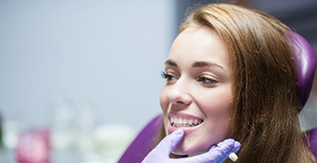 Dentist with purple glove examining patient's smile