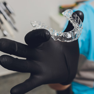 Dentist with black gloves holding Invisalign aligner