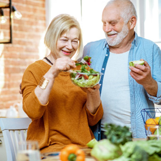 An older couple making a salad in their kitchen