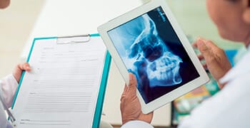 Two dentists examine x-ray on tablet