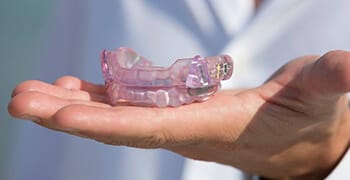 Hand holding oral appliance for TMJ therapy