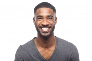 young man in black shirt smiling with perfect teeth thanks to cosmetic dentist in Tallahassee 