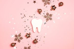 Cutout tooth with New Year decorations on a pink background