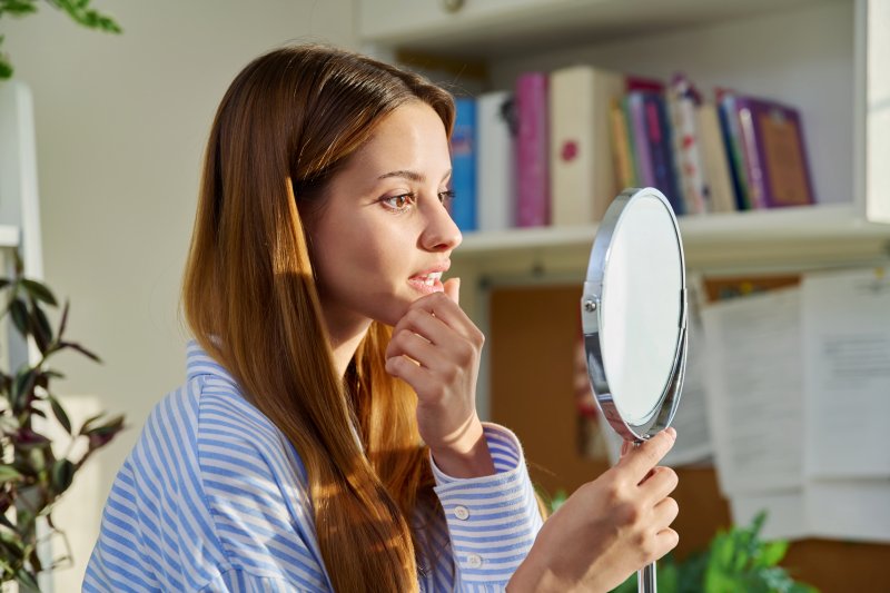 Young patient looking at face in mirror while considering BOTOX